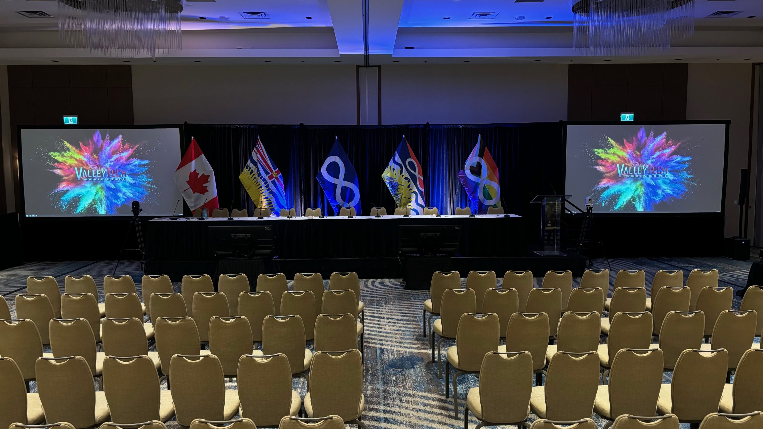 Valley Tech conference stage set in a Lower Mainland hotel ballroom — dual projection screens, head table with flags, lectern and theatre seating